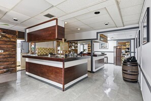 A modern reception area with a wooden reception desk, a large mirror, and a decorative fountain. - Lillooet Hotel Victoria (Lillooet)