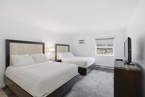 Une chambre d’hôtel avec deux lits, une télévision, une fenêtre et un bureau.