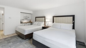 Quarto de hotel com duas camas, cozinha compacta e banheiro.
