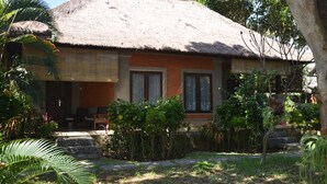 Une maison avec un toit de chaume, deux fenêtres et un petit porche.