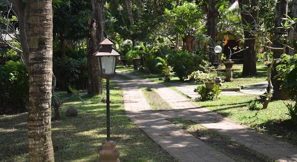 A garden pathway with a lantern post, surrounded by lush greenery and trees.