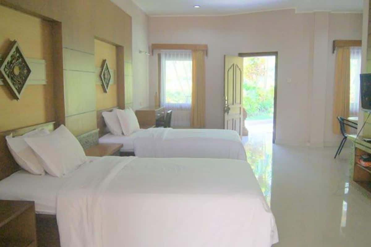 Quarto de hotel com duas camas, televisão e escrivaninha.