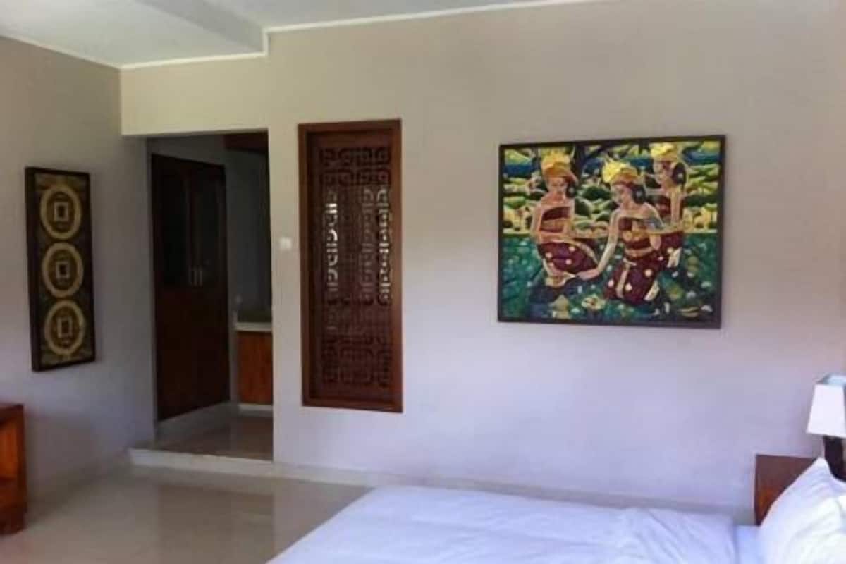 Quarto de hotel com cama, porta de madeira e quadro na parede.
