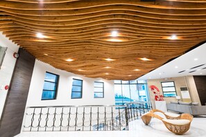 A modern interior with a wooden ceiling, a staircase, and a seating area.