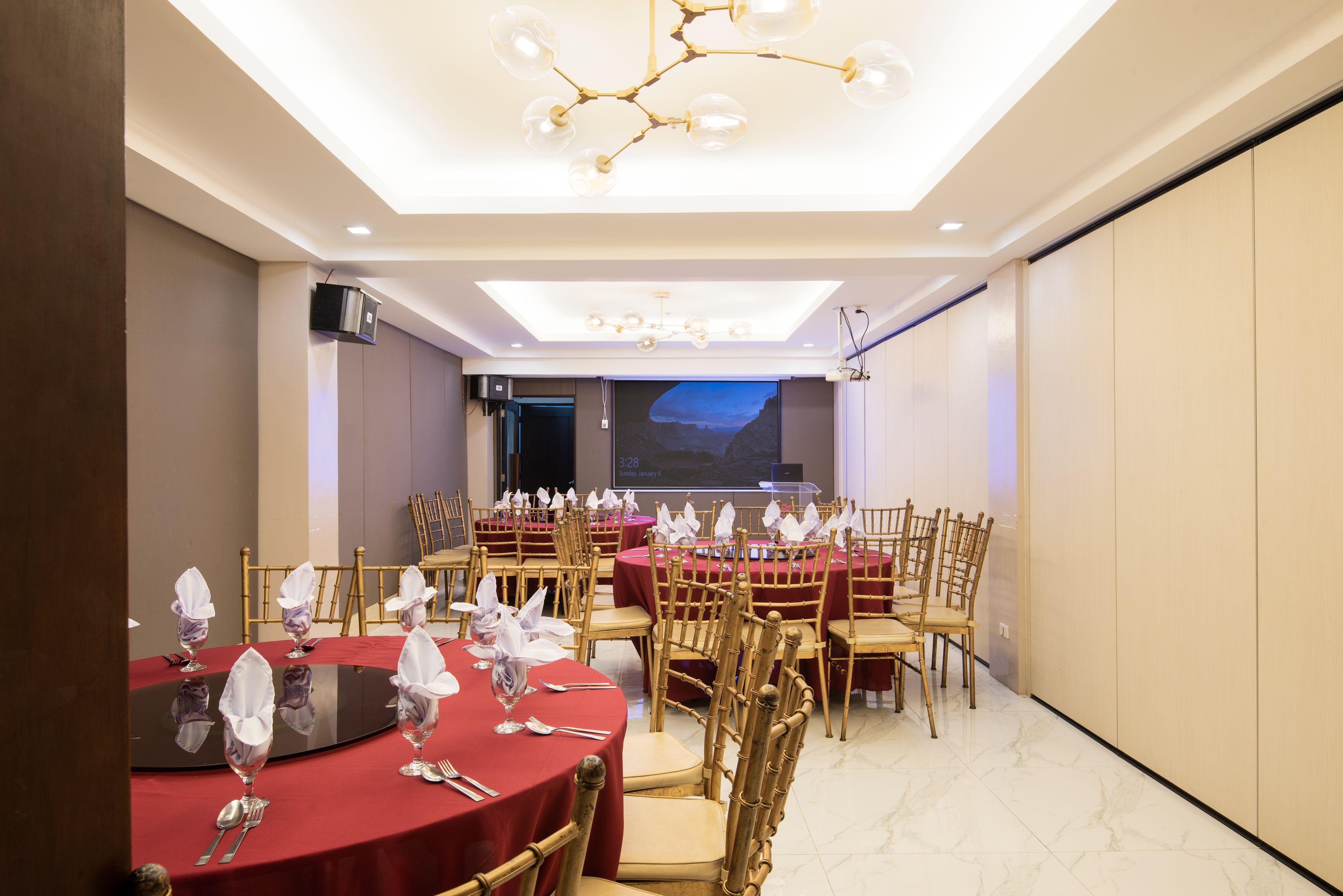 Une salle de conférence équipée de tables rondes, de chaises et d’un grand écran.