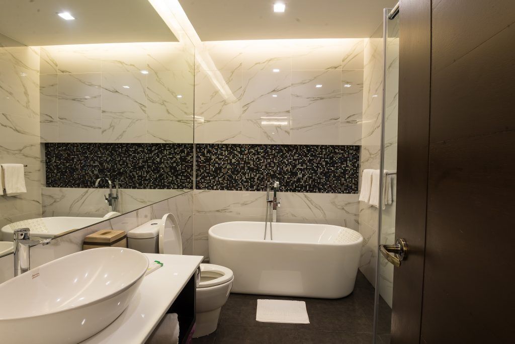 A modern bathroom with a freestanding bathtub, a large vessel sink, and a toilet.