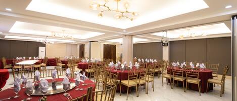 A banquet hall with round tables, chairs, and chandeliers.