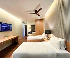 Quarto de hotel com duas camas, uma mesa, televisão e ventoinha no teto.