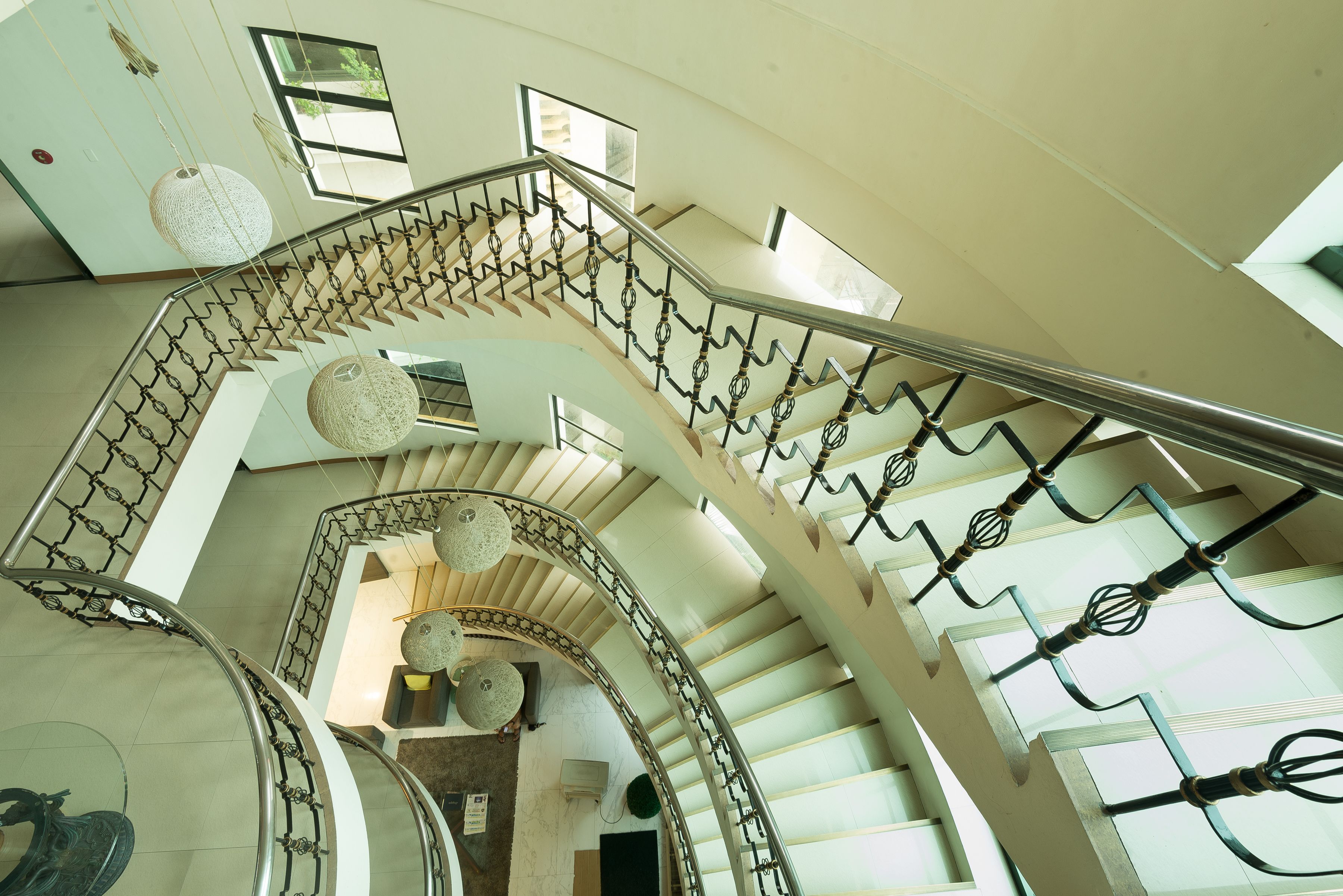 Una escalera en espiral con barandillas de metal y lámparas colgantes.