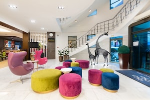 Um hall moderno com escada, assentos coloridos e uma escultura de girafa.