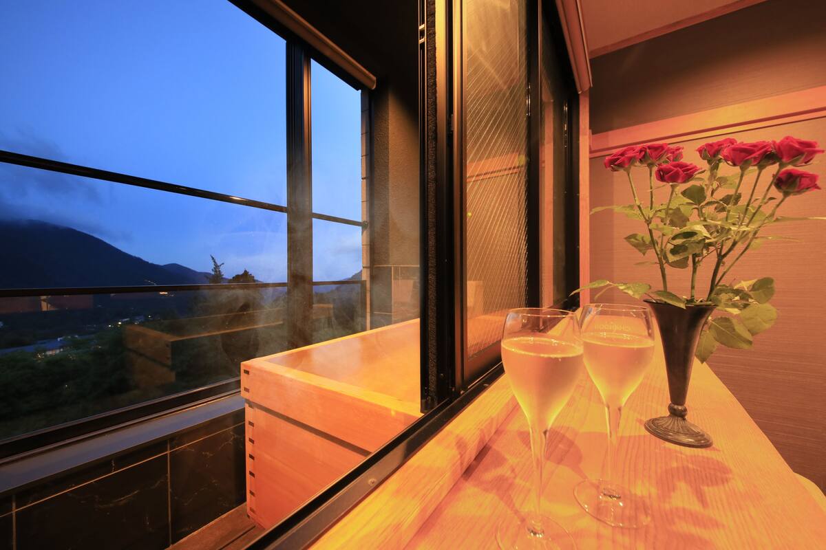 A bar area with a wooden counter, a vase with red roses, and two glasses of white wine.