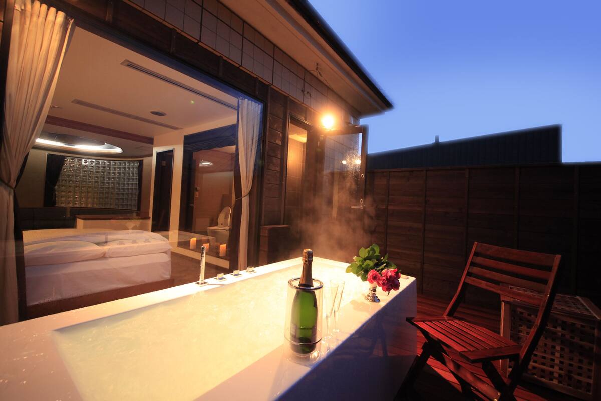 A spa area with a hot tub, a bottle of champagne, and a wooden chair.