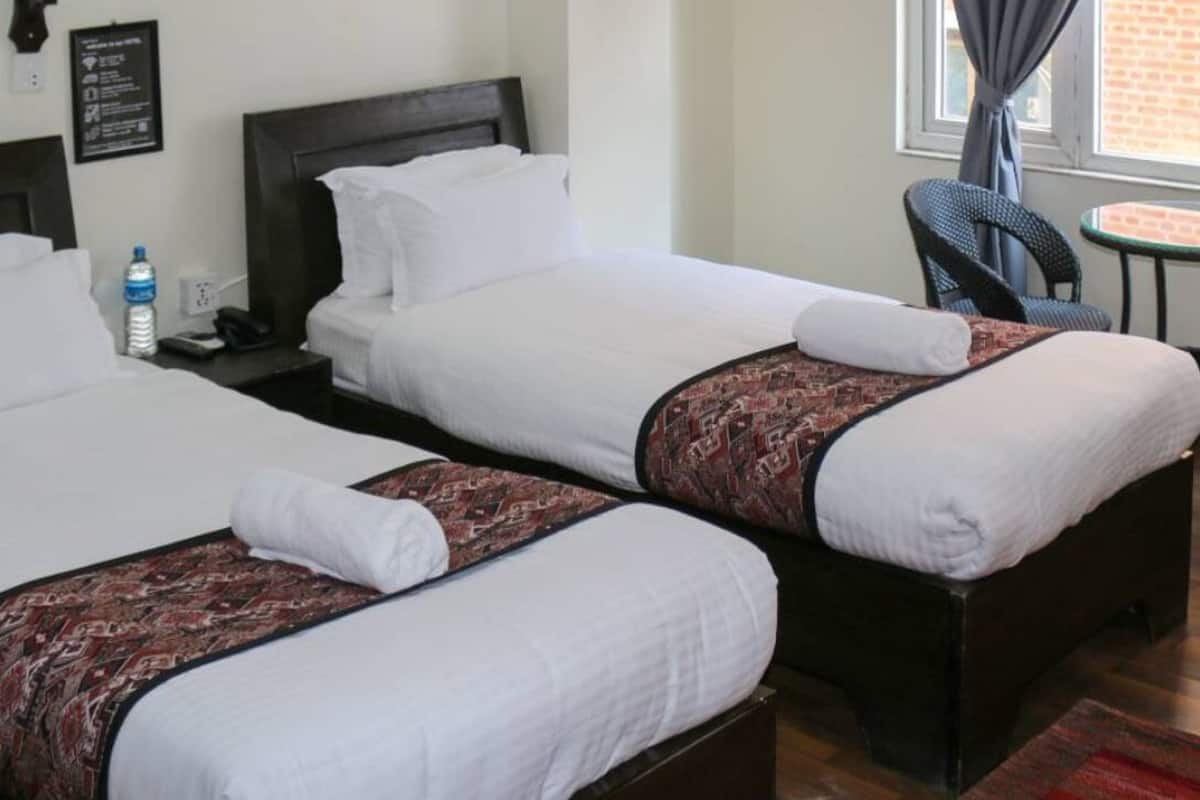 Ein Hotelzimmer mit zwei Betten, einem kleinen Tisch und Stühlen.