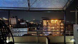 A balcony with a view of a cityscape at night, featuring a multi-story building with illuminated balconies. - Apartment Hotel 11 Thamel (Kathmandu)
