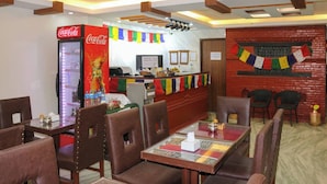 A restaurant with booths and tables, a Coca-Cola refrigerator, a counter with a menu, and colorful flags. - Apartment Hotel 11 Thamel (Kathmandu)