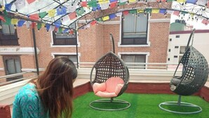 A person playing golf on a green mat with two chairs and a building in the background. - Apartment Hotel 11 Thamel (Kathmandu)