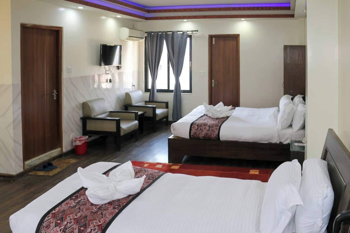 Ein Hotelzimmer mit zwei Betten, einem Fernseher, einer Couch und einem kleinen Tisch.