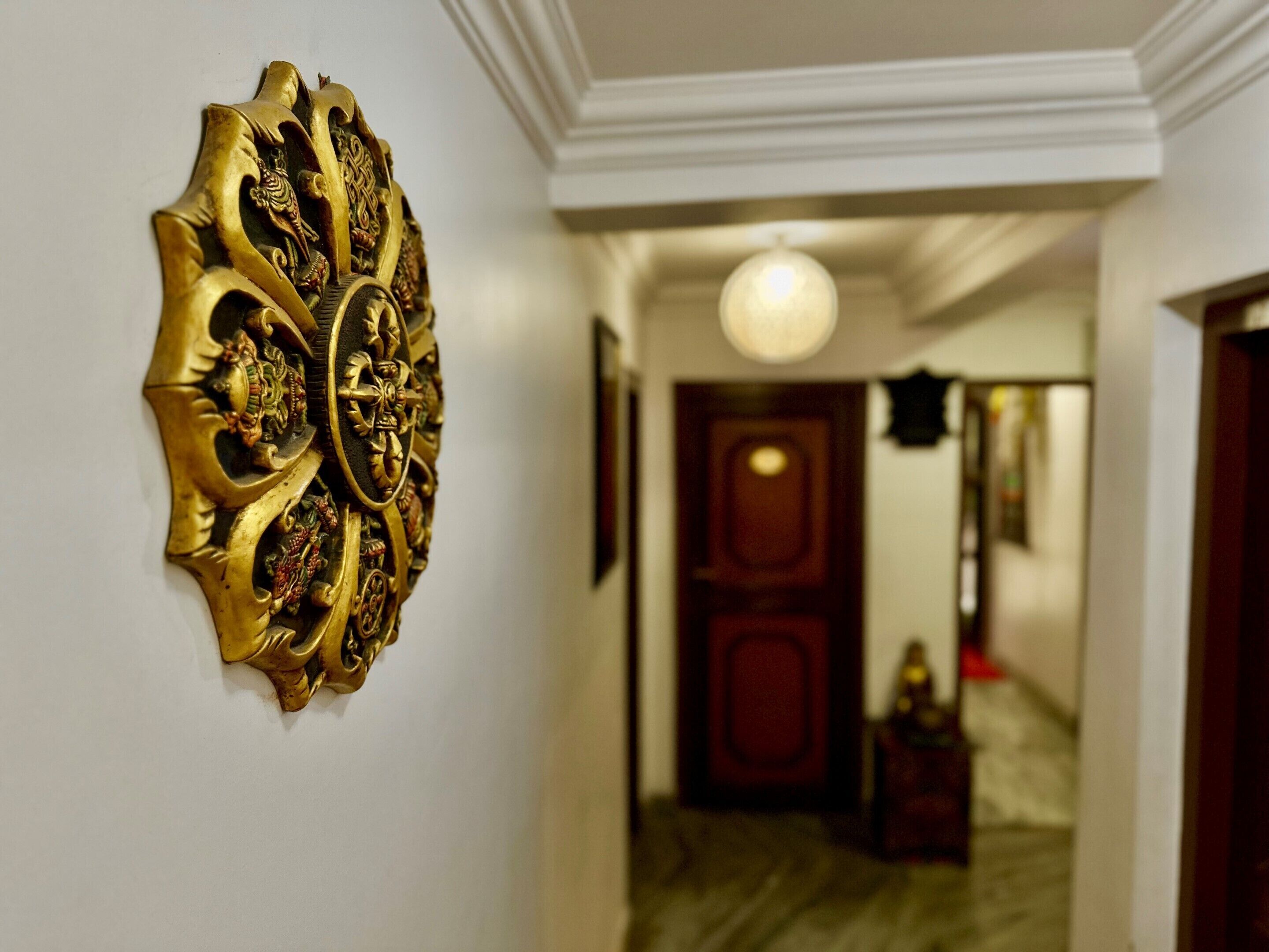 A hallway with a decorative wall piece, a door, and a light fixture.