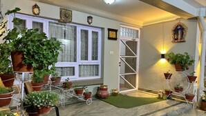 A well-lit entrance with a marble floor, potted plants, and decorative wall art. - Shakya House (Lalitpur)