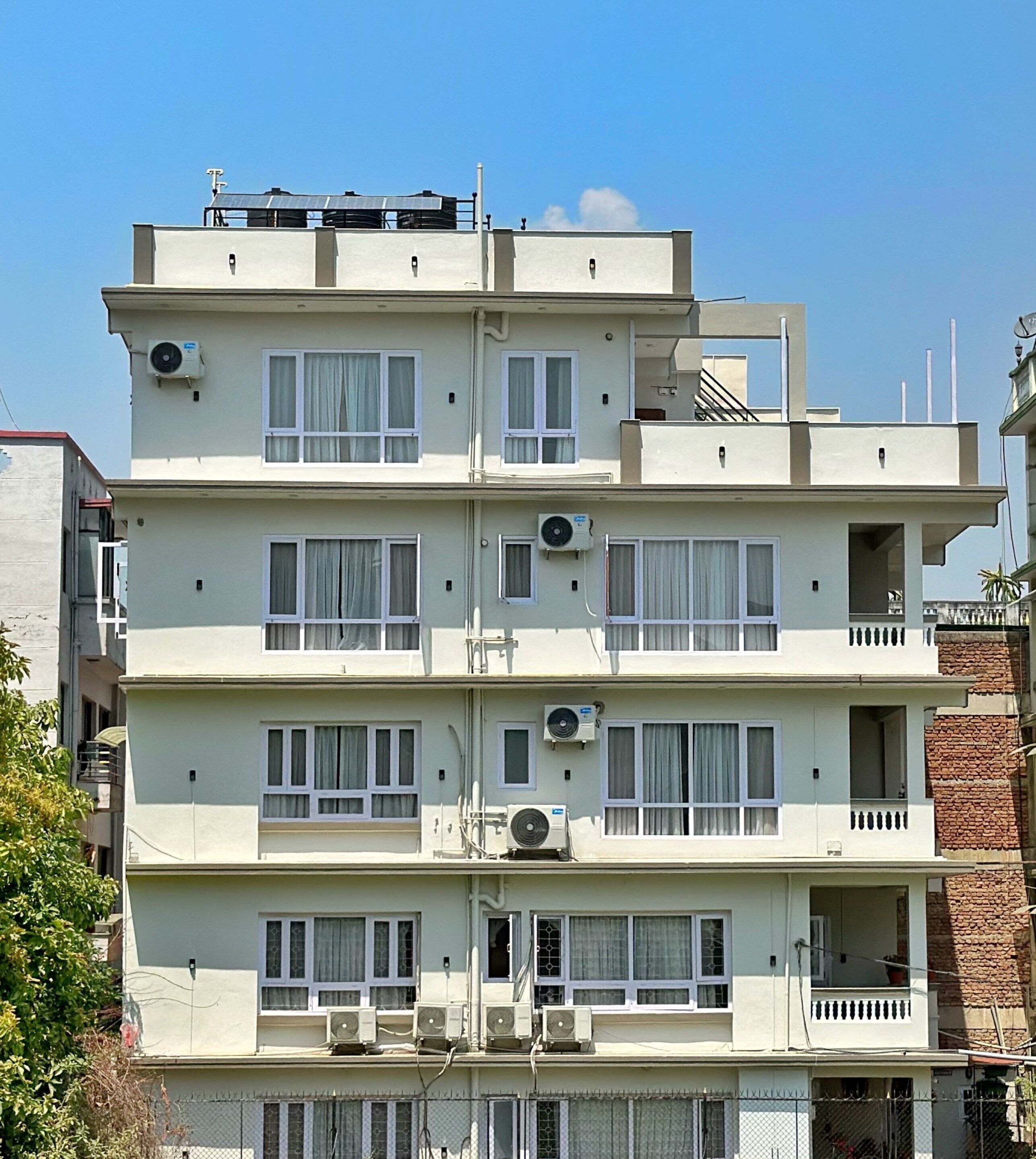 A multi-story residential building with balconies, air conditioning units, and a clear sky.