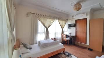 A hotel room with a bed, a desk, a chair, a TV, and a wardrobe.
