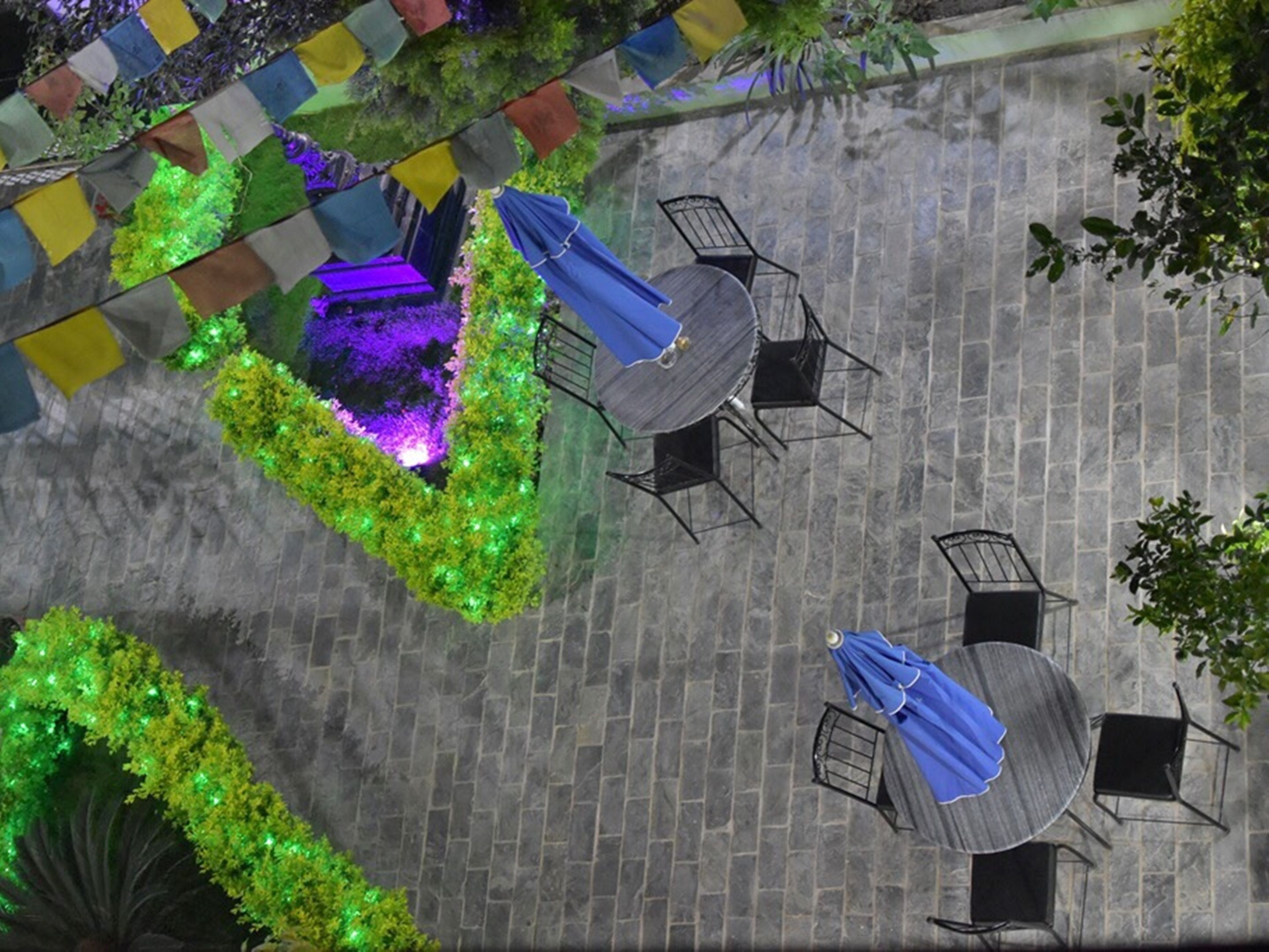 An outdoor patio area with stone flooring, round tables, and black metal chairs.