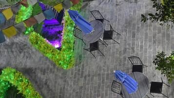 An outdoor patio area with stone flooring, round tables, and black metal chairs.