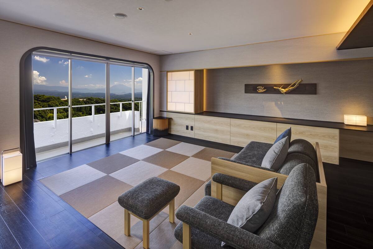 Ein modernes Wohnzimmer mit einem großen Schiebeglastür, die auf einen Balkon führt, einer Sofaecke und einer minimalistischen Küchenzeile.