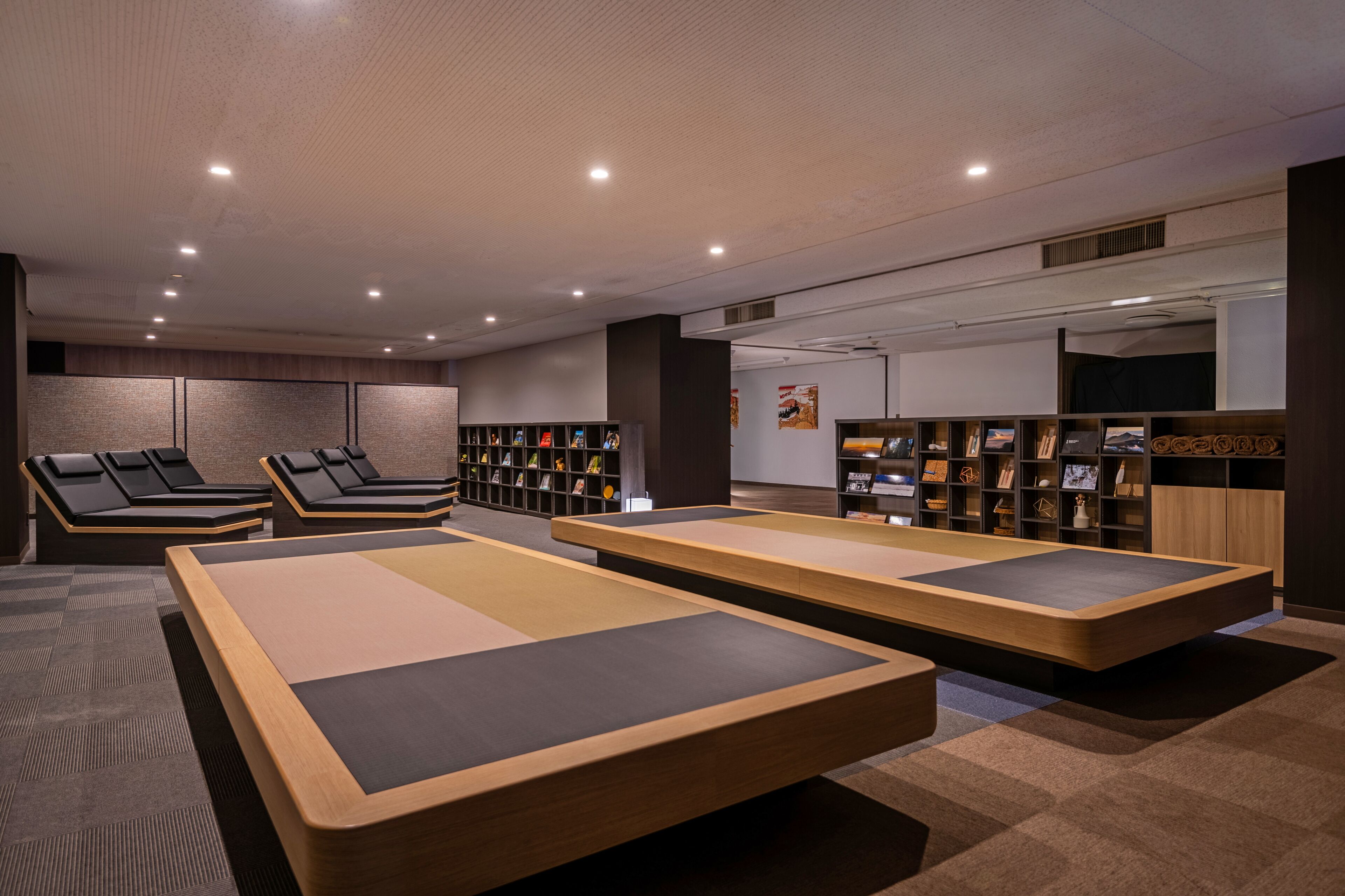 A modern spa room with massage tables, a reception desk, and a wall of framed pictures.