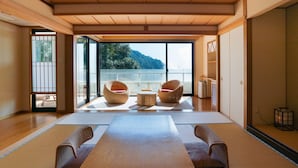 Een traditionele Japanse kamer met tatami vloerbedekking, een lage houten tafel en twee rieten stoelen met rode kussens.