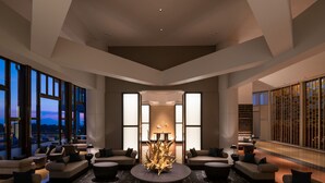 Een moderne lounge met banken, een centrale tafel en grote ramen met uitzicht op de skyline.