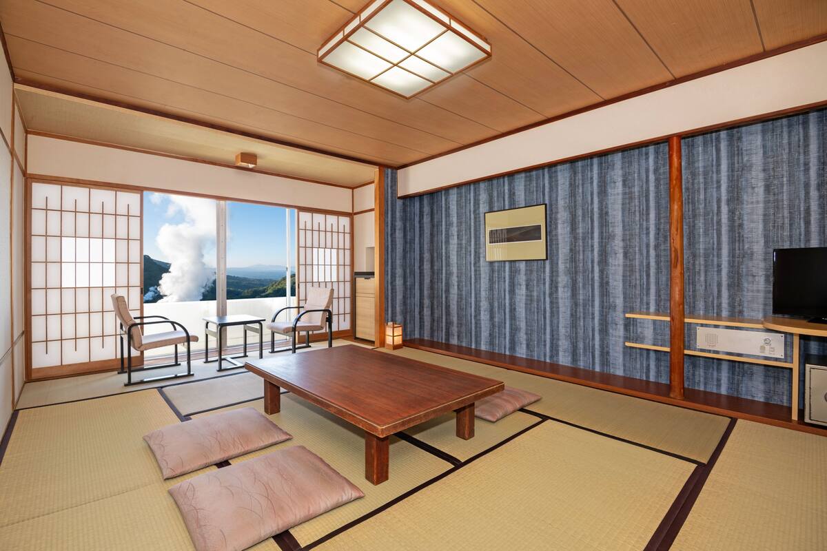 Ein traditioneller japanischer Raum mit Tatami-Böden, einem niedrigen Holztisch und Schiebetüren zu einem Balkon mit Meerblick.