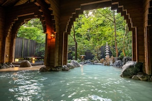 A serene indoor water feature with a wooden structure, rocks, and a pagoda.