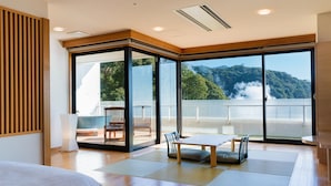 Une chambre d’hôtel moderne dotée d’une grande porte-fenêtre coulissante donnant sur un balcon avec vue sur les montagnes.