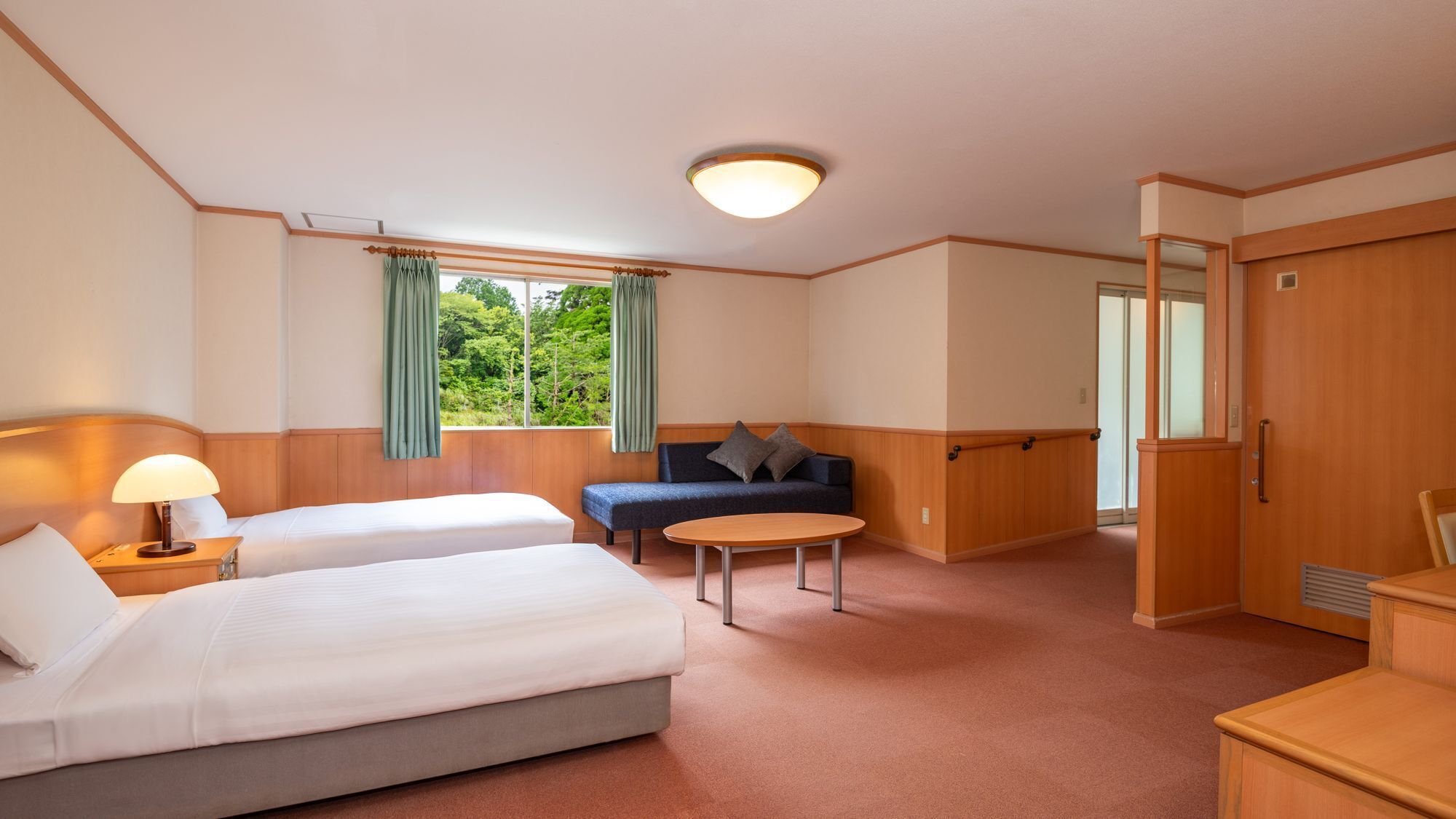 Une chambre d’hôtel avec deux lits, un canapé, une table ronde et une armoire.