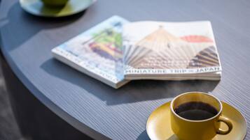 A table with a magazine titled 'Miniature Trip to Japan' and a cup of coffee on a saucer.