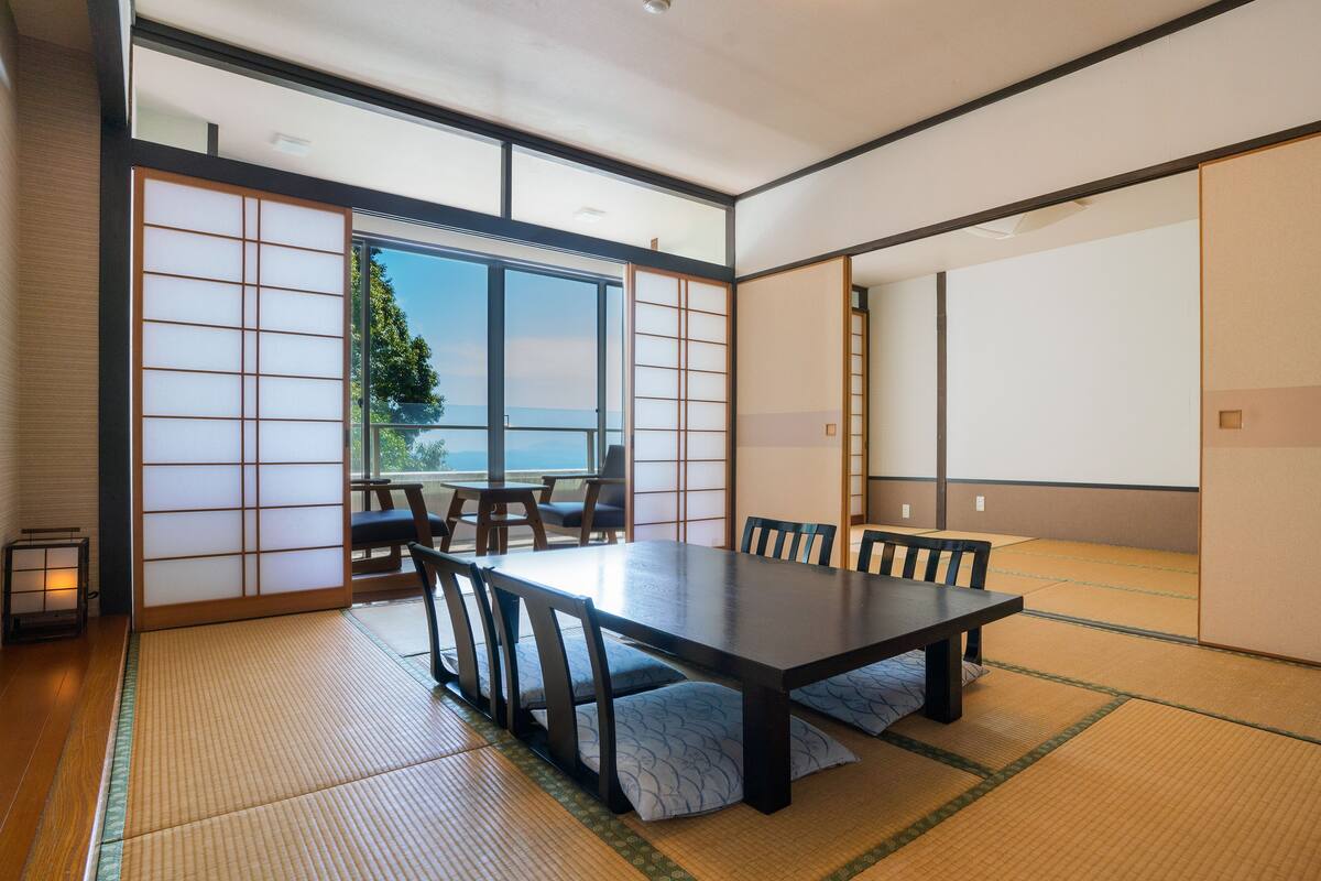 Ein traditioneller japanischer Raum mit Tatami-Böden, einem niedrigen Tisch und verschiebbaren Türen.