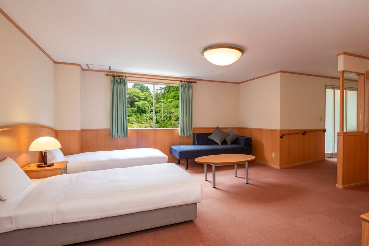Ein Hotelzimmer mit zwei Betten, einem Sofa, einem Tisch und einem Kleiderschrank.