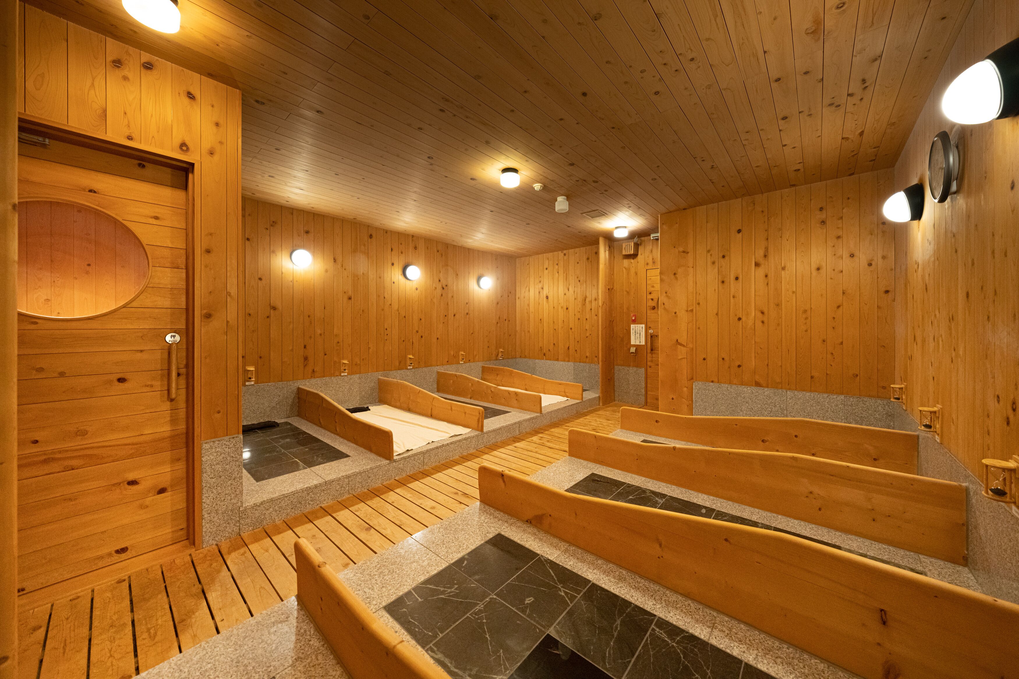 A wooden sauna with multiple benches and a tiled floor.
