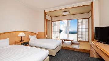 A hotel room with two beds, a desk, a TV, and a view of the outdoors.