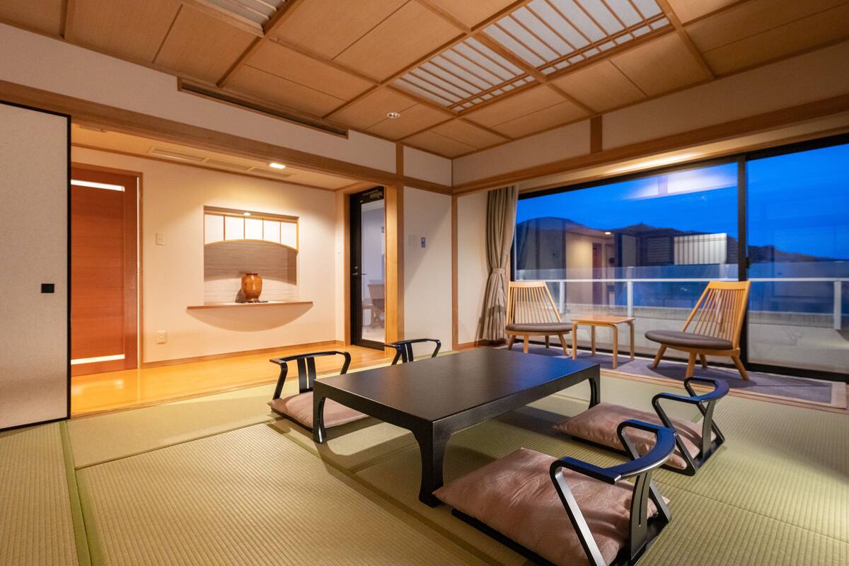 Ein traditioneller japanischer Raum mit Tatami-Böden, einem niedrigen Tisch und Holzstühlen.