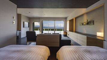 Quarto de hotel moderno com duas camas, uma escrivaninha e uma janela ampla com vista para as montanhas.