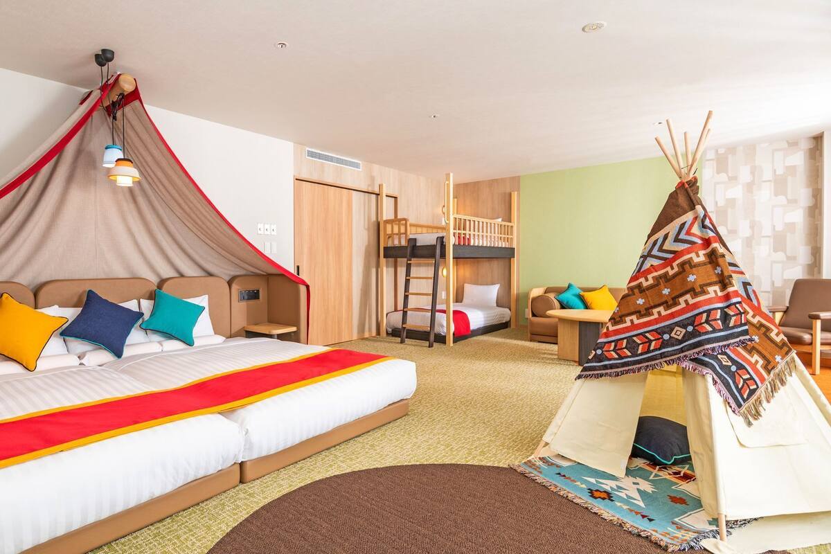 Ein Hotelzimmer mit einem großen Bett, einem Himmelbett, einem Etagenbett, einem Zelt und einem Sofa.