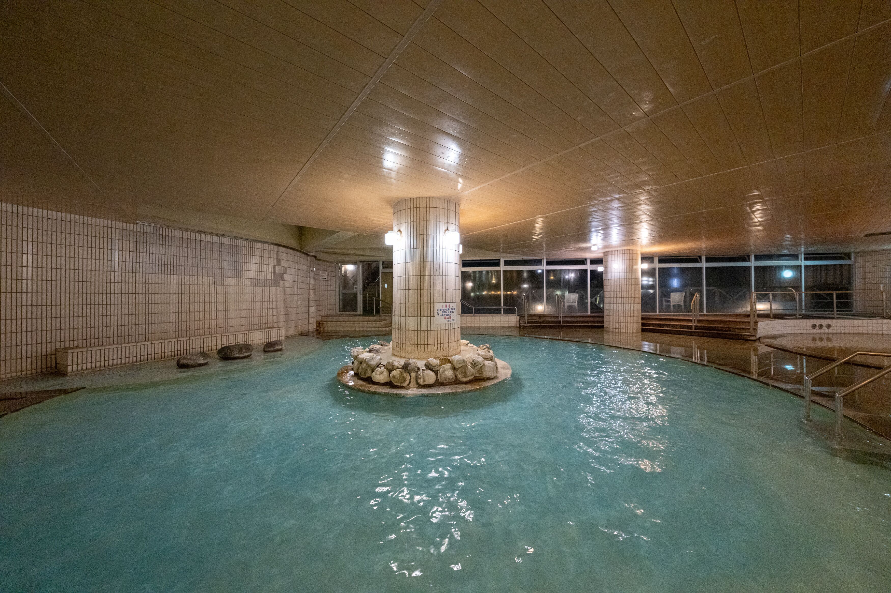Une piscine intérieure dotée d’une colonne centrale et de murs carrelés.