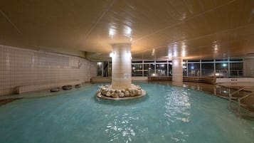 Une piscine intérieure dotée d’une colonne centrale et de murs carrelés.