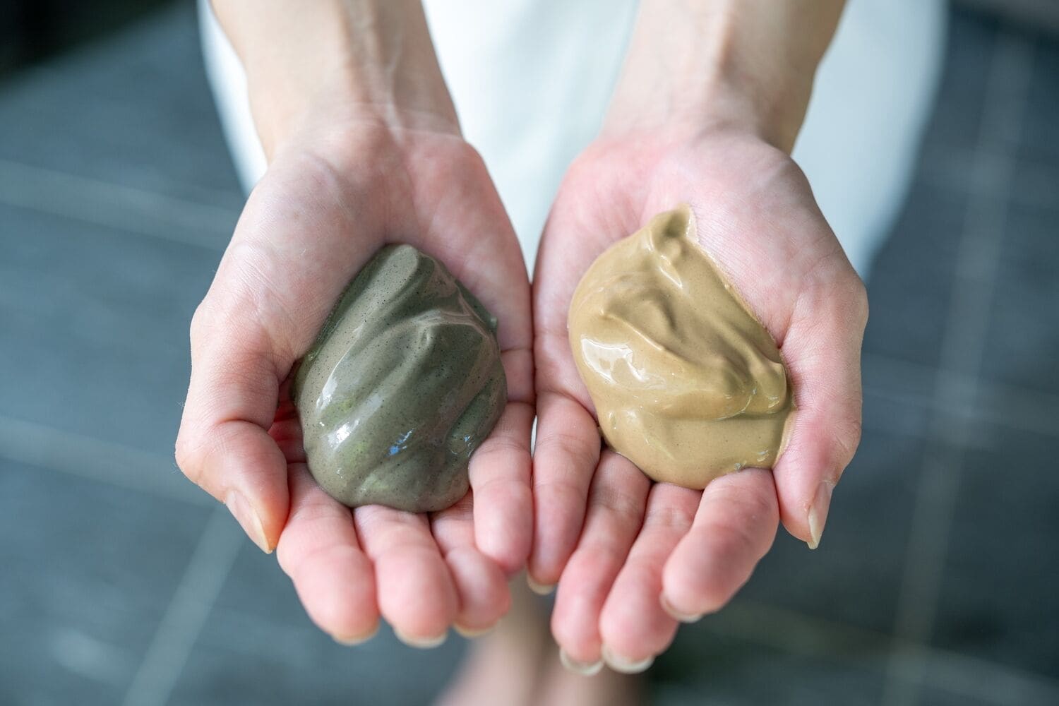 Two hands holding different textured substances.