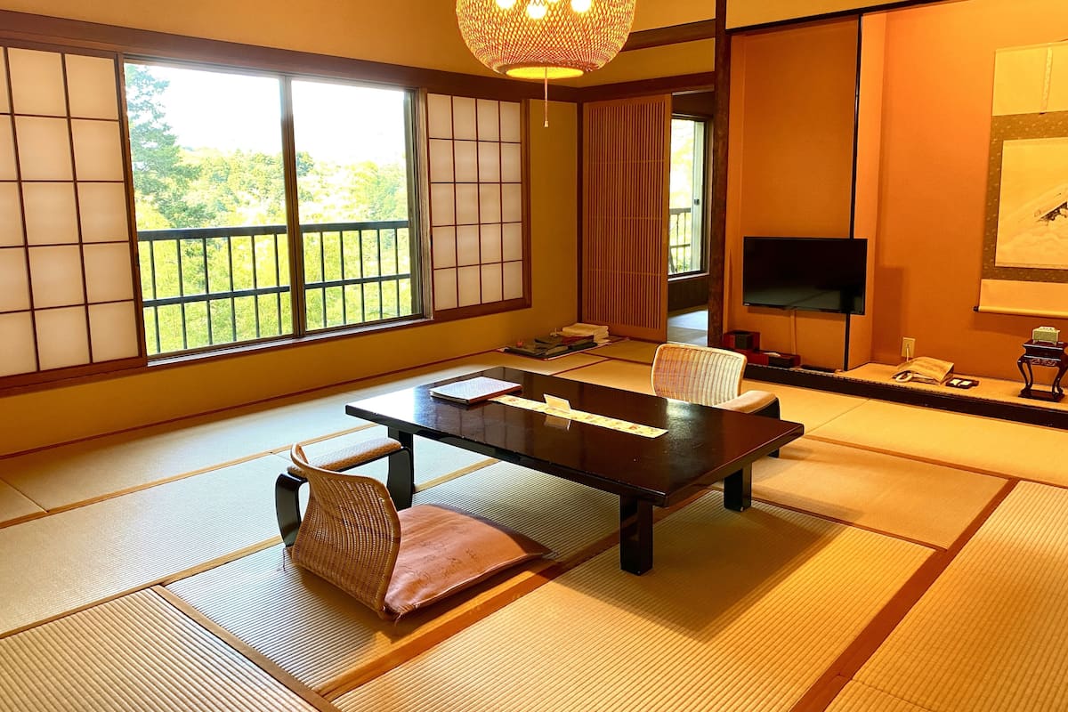 A traditional Japanese room with tatami flooring, a low table, and a woven chair.