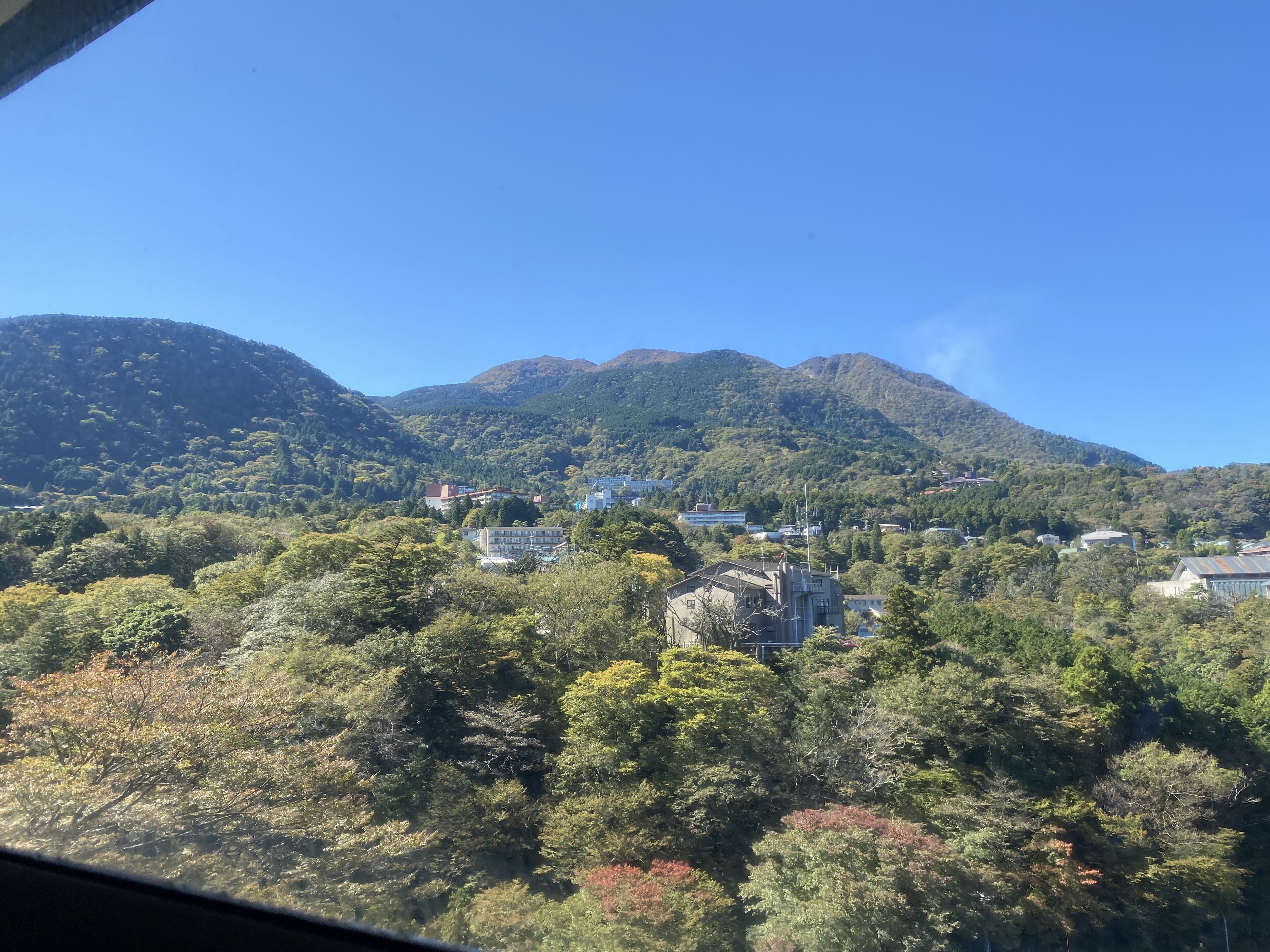 Un paisaje montañoso con edificaciones ubicadas entre árboles.