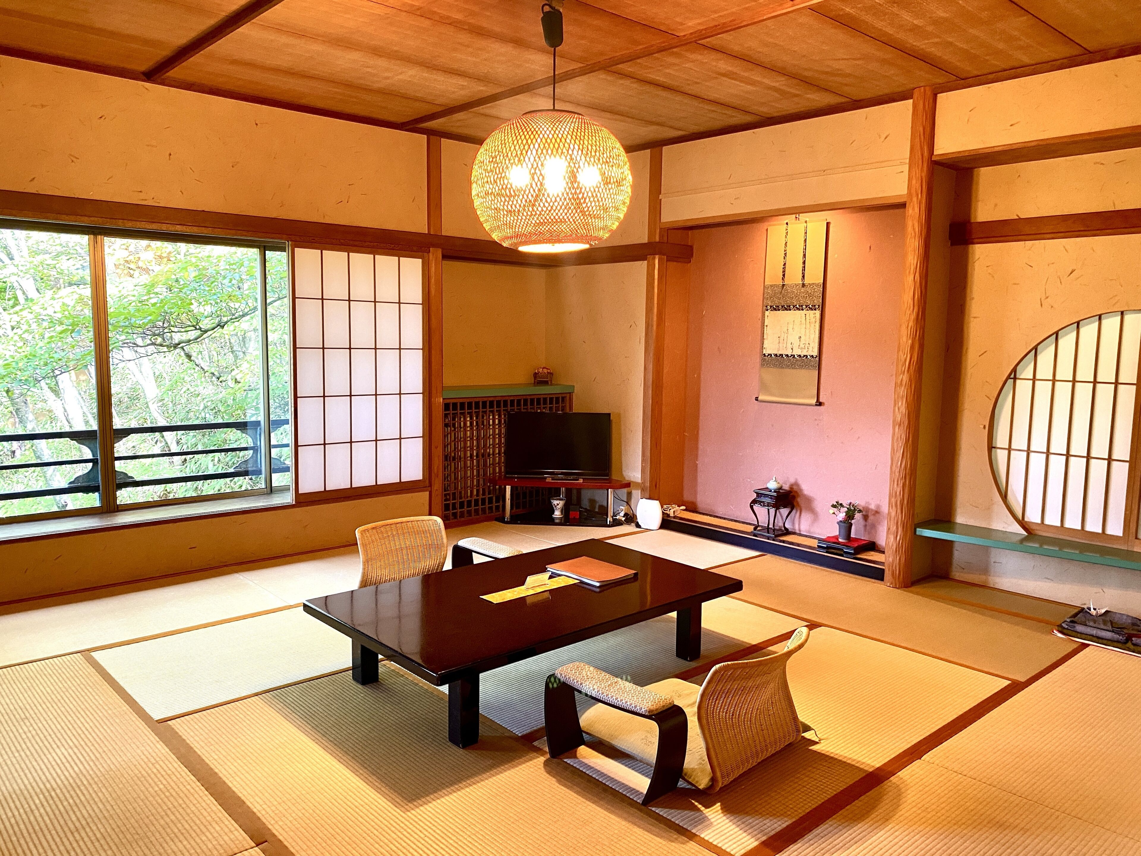 Una habitación japonesa tradicional con suelo de tatami, una mesa baja y un televisor.