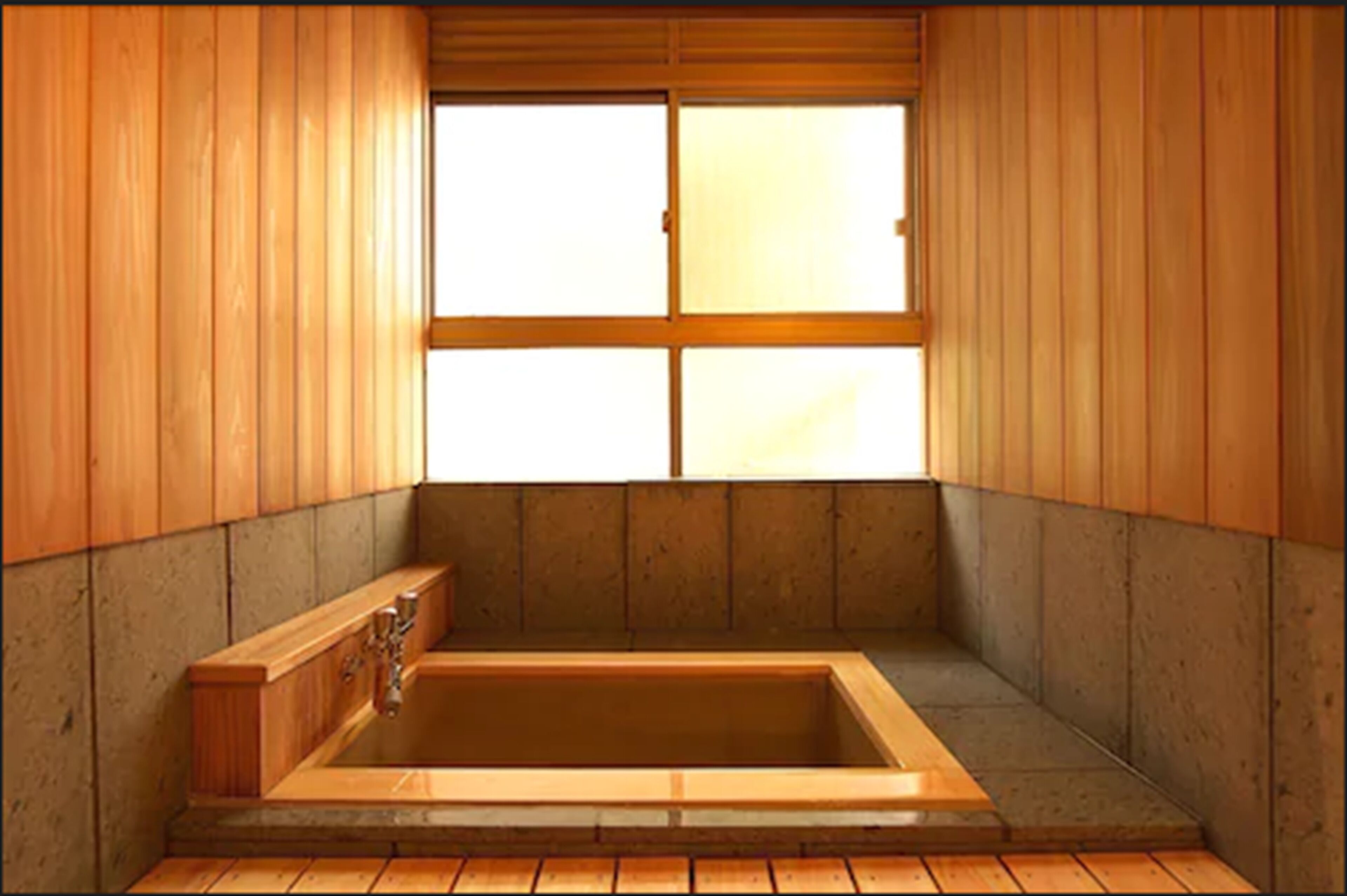 Una habitación tradicional japonesa con interiores de madera, una amplia bañera de madera y un ventanal con puertas correderas shoji.